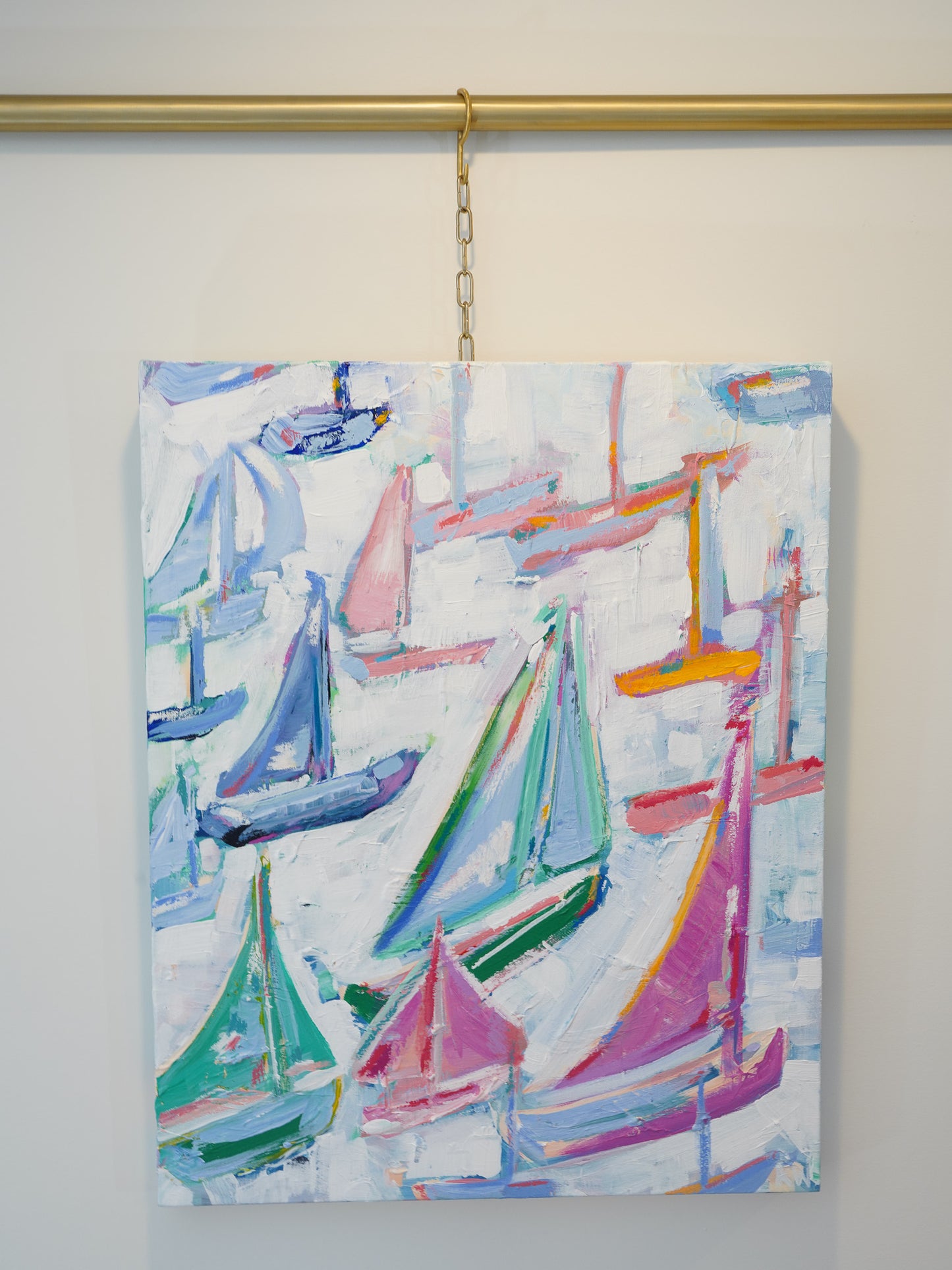 A medium sized acrylic and oil pastel painting. Thick brush strokes and lots of layers create a dynamic and interesting canvas. Vibrant hues of peaches, pinks, oranges, greens and blues are used to depict many overlapping sailboats in an abstract style.