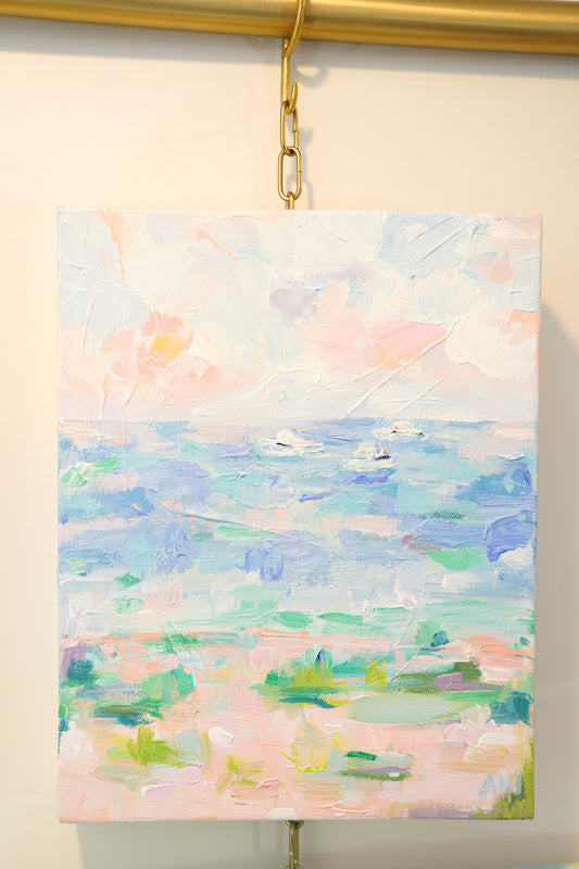 A small acrylic painting depicting a beach scene with three boats in the distance. Pastel colors in pinks blues and greens create a serene feeling. 